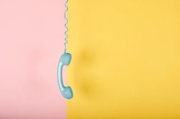 Blå telefonlur som hänger över färgrann bakgrund mindre FB